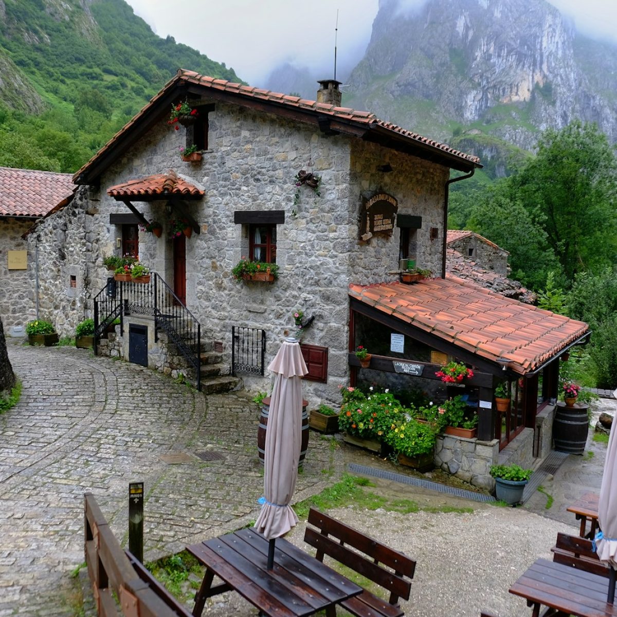 a stone building with tables and umbrellas in front of it
