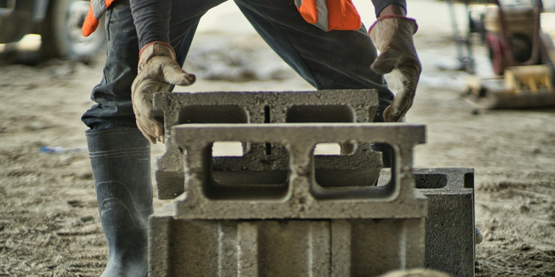 a man in an orange vest is working on a concrete block